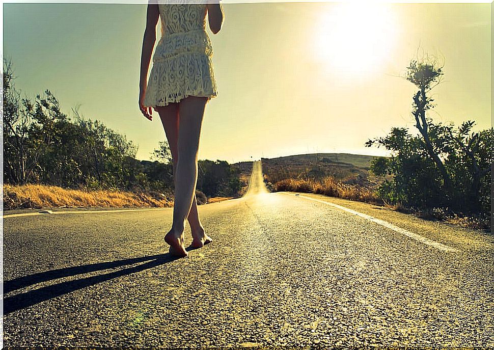 Girl walking barefoot on a tarmac road