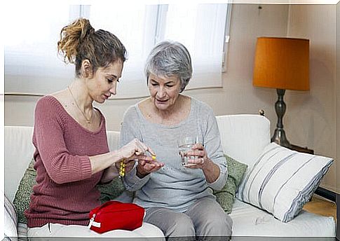 Woman helping elderly woman take her medicines as an example of informal care