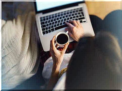 A woman drinks coffee and works on her computer