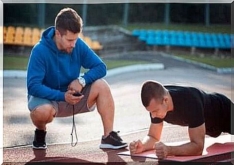 A trainer watches an athlete push up