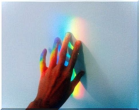 Hand touches rainbow as an example of the gift of highly sensitive people.