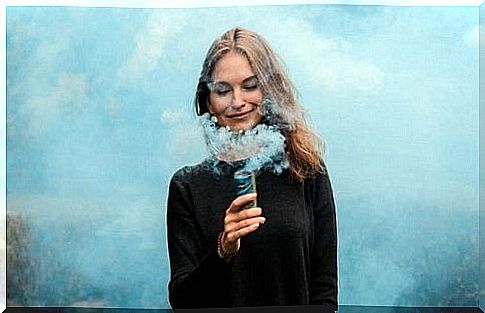 Woman holding a smoke bomb in front of her face but still smiling